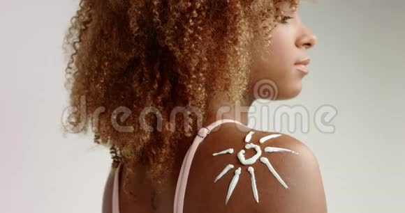 黑混血金发女人肩上涂防晒乳液晒太阳然后弄脏视频的预览图