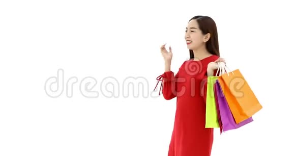 亚洲女人拿着购物袋她移动着自己的身体和姿势购物狂女人的概念白色背景的摄影棚视频的预览图