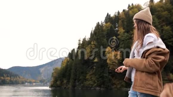 美丽的白种人女女孩站在山上美丽的湖泊附近扔了一块石头慢节奏视频的预览图