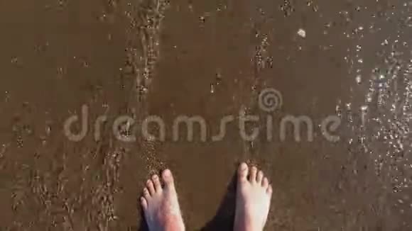 游客脚在鹅卵石上用泡沫小浪淘洗在海边休息视频的预览图