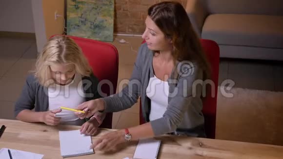 年轻的白种人母亲教她的小漂亮女孩并给她一个数学任务的特写照片视频的预览图