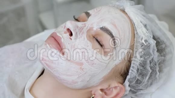 女孩躺在医生的桌子上美容师拿着白色的奶油视频的预览图