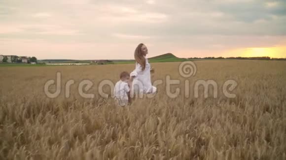 母子两人在金色麦田上奔跑牵着手母观念幸福家庭慢动作视频的预览图