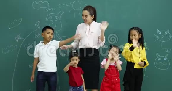 亚洲老师和学生挥舞着手他们站在绿色的墙前视频的预览图
