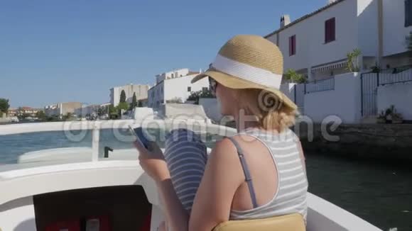 女游客在运河上的一艘小船上航行使用手机西班牙埃姆普里布拉瓦视频的预览图