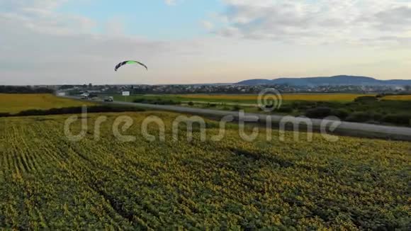 日落时分摩托降落伞沿着向日葵球场上方的道路飞行视频的预览图