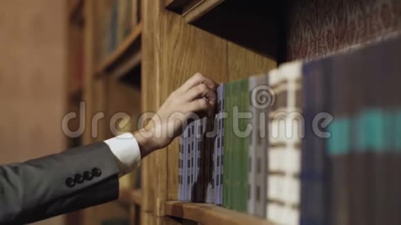 公共图书馆的男性右手选择和挑选书籍从选定的教科书中提取教育研究和自我视频的预览图
