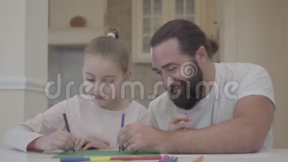 大胡子爸爸和一个漂亮的小女儿在一天假的时候坐在一张桌子上画着焰火帕斯蒂父亲和视频的预览图