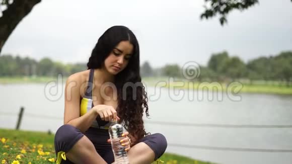 运动的年轻女子喝凉水的肖像视频的预览图