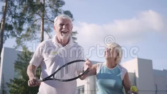 快乐的成年夫妇在阳光明媚的日子打网球一个老男人和一个成熟的女人喜欢这个游戏娱乐和休闲视频的预览图