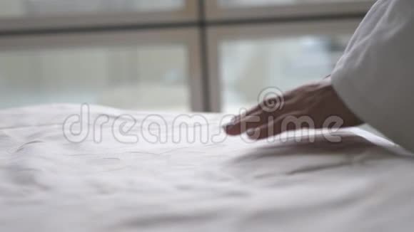 女人的手滑过一张白色的床单来整理它关门视频的预览图