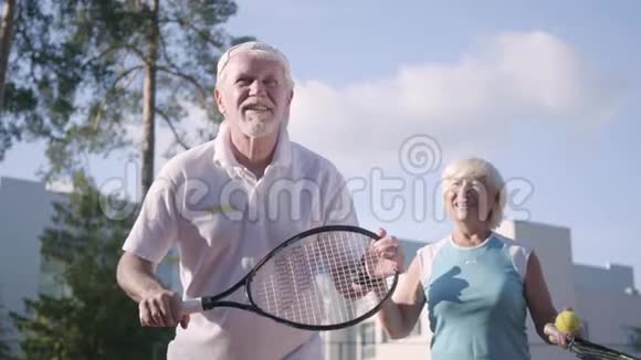 一对成年夫妇在阳光明媚的日子打网球一个老男人和一个成熟的女人喜欢这个游戏娱乐和休闲视频的预览图