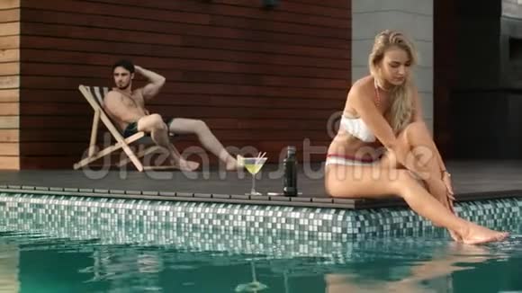 性感的女人坐在游泳池附近游泳池边的漂亮女孩视频的预览图