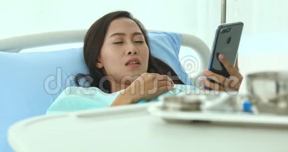 亚洲女性患者使用智能手机与朋友交谈并闭上眼睛视频的预览图