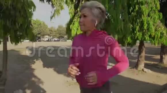 万向节跟踪有吸引力的中年女士在城市公园跑步快乐40多岁的美女正在慢跑视频的预览图