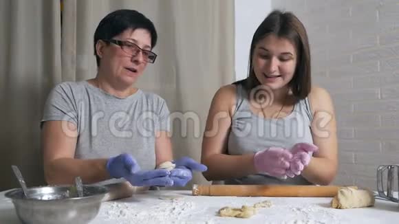 一个怀孕的女孩和她的母亲坐在家里厨房的一张桌子旁午餐准备饺子和肉末卷起来视频的预览图