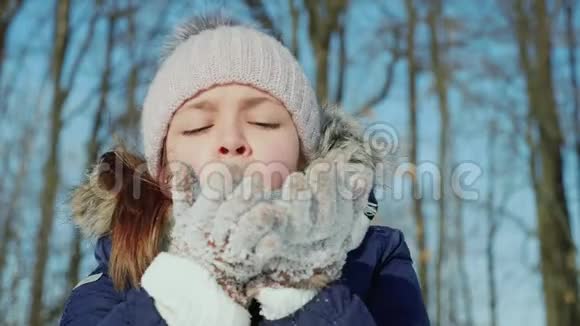 少女在冬天用针织手套吹雪花视频的预览图