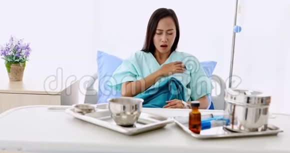 亚洲女性病人有胸痛躺在病人床上桌子上有医疗设备在医院视频的预览图