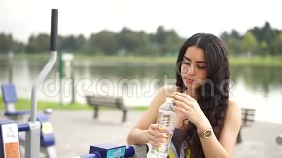运动的年轻女子喝凉水的肖像视频的预览图