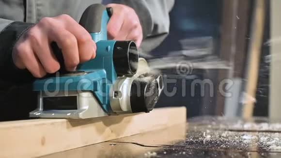 木工在家庭车间用电平面工作的手的特写在慢速运动中整理木制部件视频的预览图