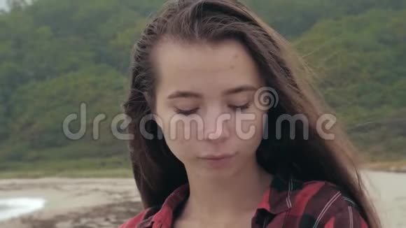 在热带海滩上大海背景下美丽的年轻欧洲女孩身着格子衬衫的特写肖像视频的预览图