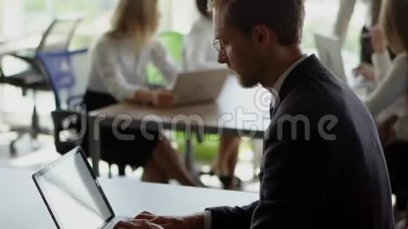 一个商人在他的笔记本电脑上打字老板在后台向工人解释新想法视频的预览图