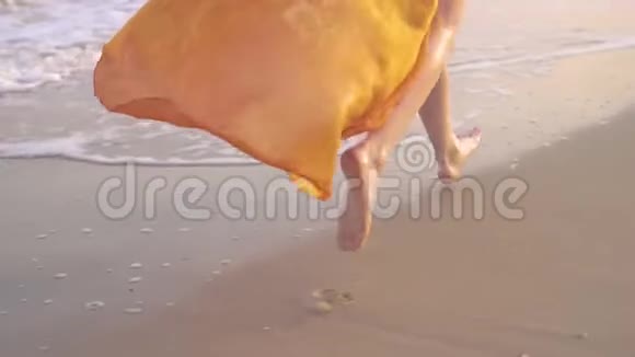 日落时女性光着脚和飘舞的裙子年轻的赤脚女孩穿着长裙子沿着冲浪线跑视频的预览图