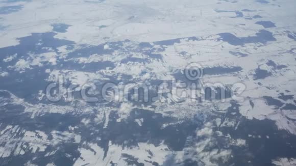 从飞机上俯瞰白雪皑皑的冬季田野和云层视频的预览图