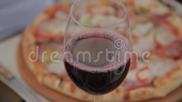一杯红酒放在桌上背景是新鲜披萨视频的预览图