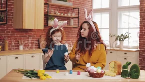复活节快乐年轻的母亲和她的小女儿互相画鸡蛋和脸家庭笑话视频的预览图