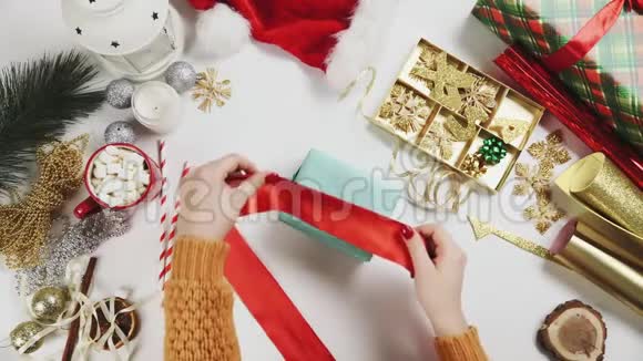 女人包装圣诞礼物白色桌子背景的礼物节日装饰视频的预览图