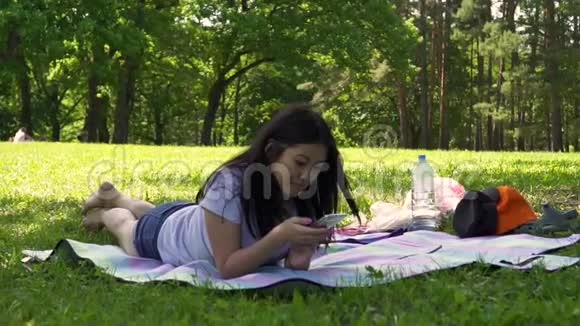 年轻的亚洲女孩躺在公园的空地上每天写一封信视频的预览图