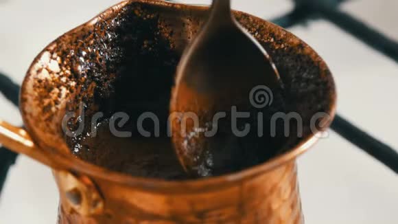 一茶匙将黑咖啡混合成一个铜土耳其它矗立在白色煤气炉上视频的预览图