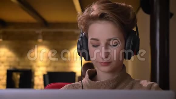年轻的短发女人的特写肖像放下耳机在办公室里愉快地看着镜头视频的预览图