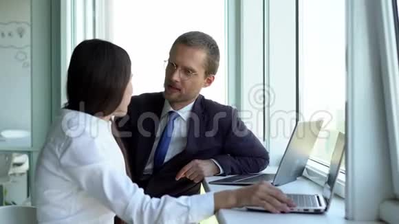 商人和黑发的女商人在工作时可爱地说话坐在办公室的窗户旁视频的预览图