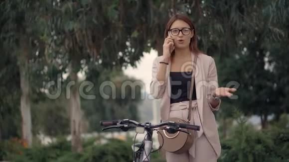 年轻愤怒的女人在夏天的公园里用手机说话视频的预览图