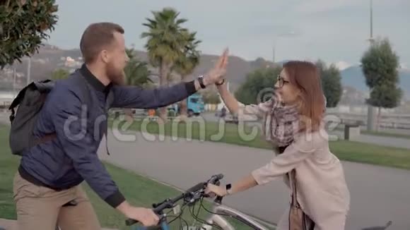 两个快乐的朋友一边说一边骑自行车视频的预览图