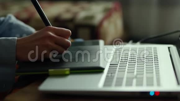 用钢笔平板电脑和笔记本电脑做特写在家工作的女性自由职业者退休人员视频的预览图