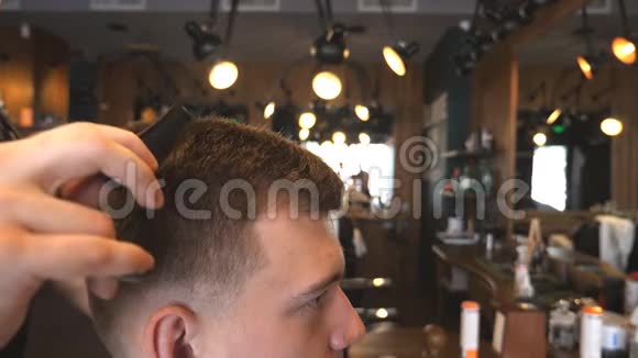 理发店年轻男士梳头的理发师男手帅小伙在沙龙理发切割视频的预览图
