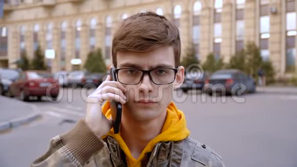 集中精力的年轻人戴着眼镜耳朵旁拿着电话视频的预览图
