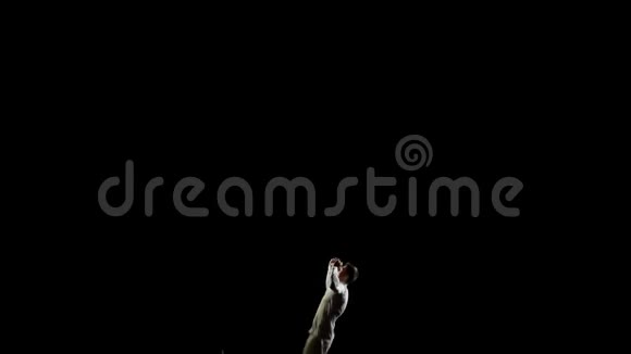 美丽的白人男子体操运动员在黑色背景下慢动作旋转和翻转做杂技特技视频的预览图