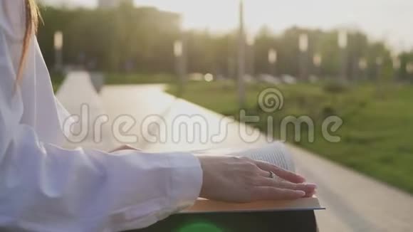 年轻女子坐在公园的长凳上看书视频的预览图