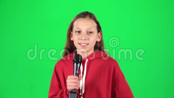 女孩在演播室绿色背景下唱成麦克风慢动作视频的预览图