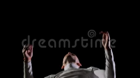 慢动作男子穿着白色衣服在黑色背景上跳跃旋转表演杂技后翻中等视频的预览图