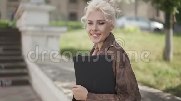 快关门年轻的学生拿着笔记本电脑靠近她的高脚凳微笑和快乐视频的预览图