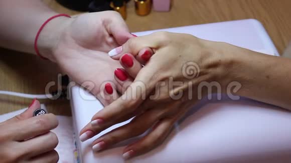 女性指甲抛光漫画家在工作的最后一步将白色清漆涂在拇指指甲上视频的预览图