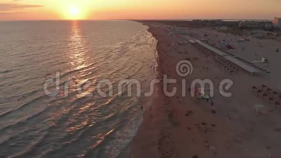 鸟瞰美丽的日落越过大海和沙滩人们在海浪中游泳视频的预览图