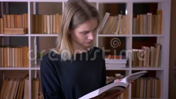 在大学图书馆里一位年轻有魅力的女学生正在看一本书看着室内的摄像机视频的预览图