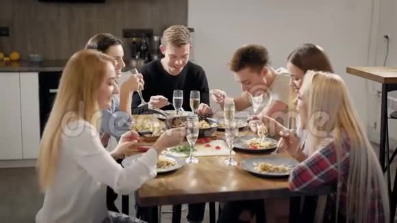 一群年轻的室友坐在桌边吃饭一边喝着酒杯一边说着祝酒词视频的预览图