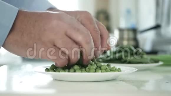 厨房中的男人选择和新鲜的绿色豌豆烹饪视频的预览图